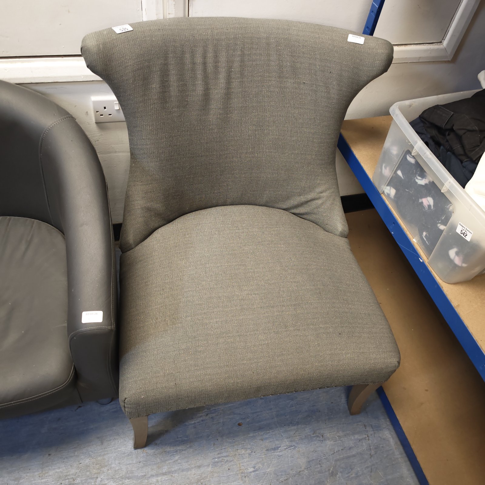 Grey fabric bedroom chair with curved back and wooden legs.