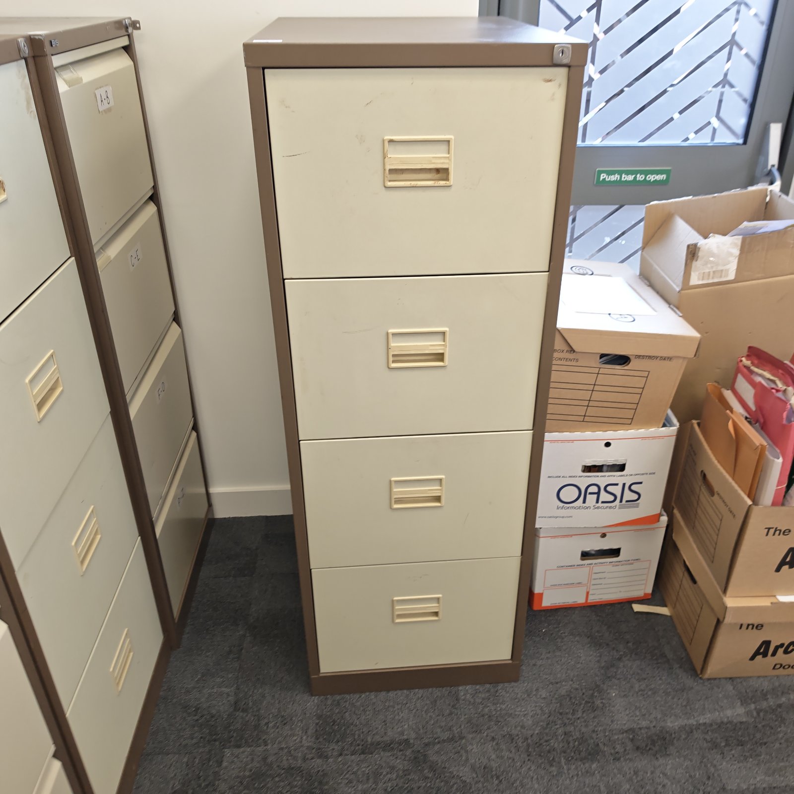 Grey metal filing cabinet with four drawers for office storage.