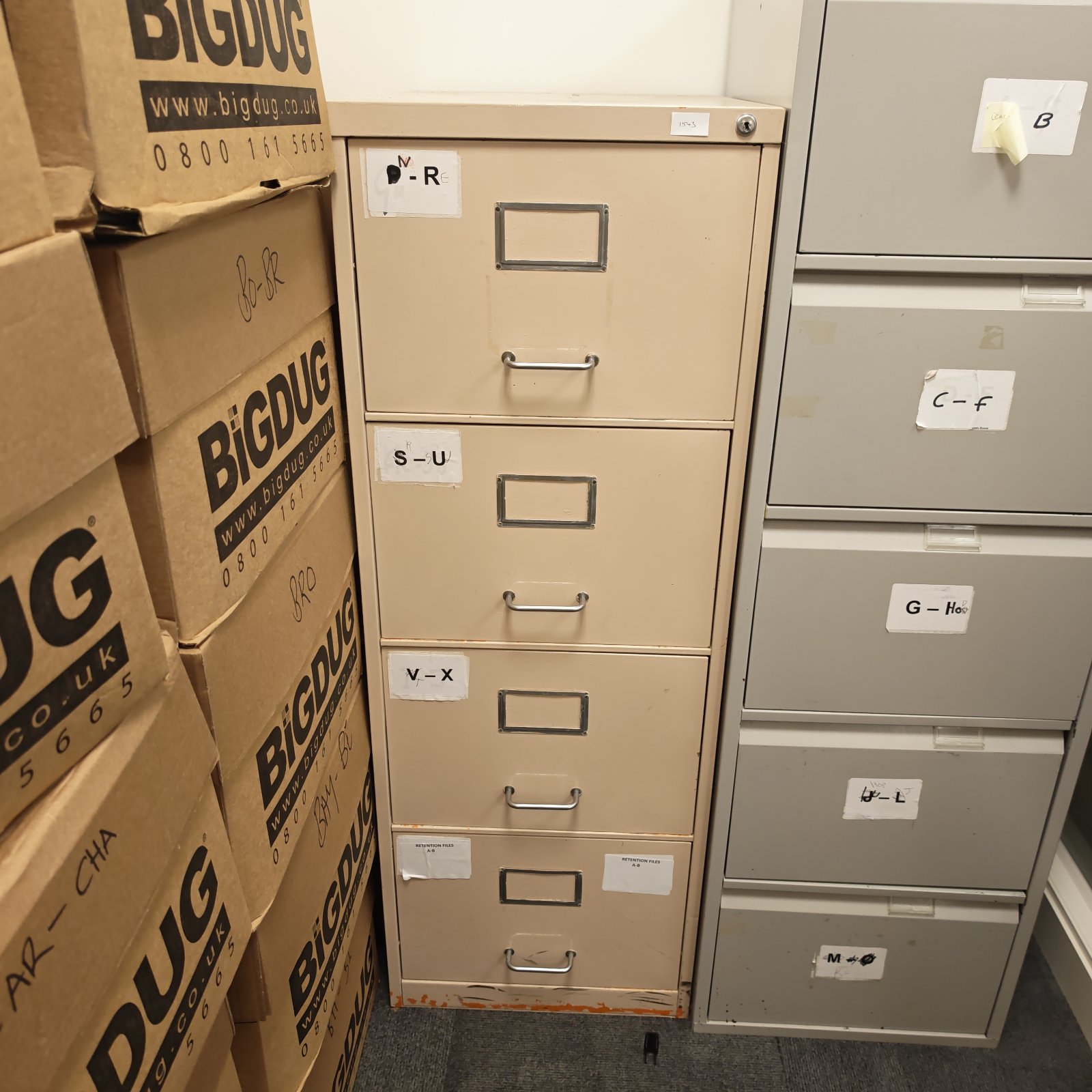Grey metal filing cabinet with four drawers, showing signs of wear.