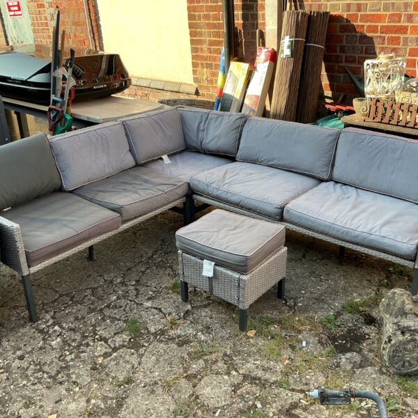 Grey poly rattan corner sofa set with cushions in a garden setting.
