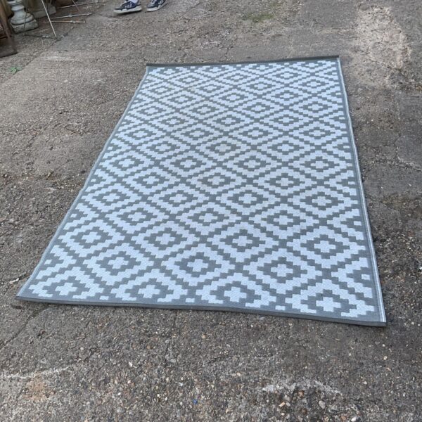 Grey and white patterned outdoor rug on a patio.