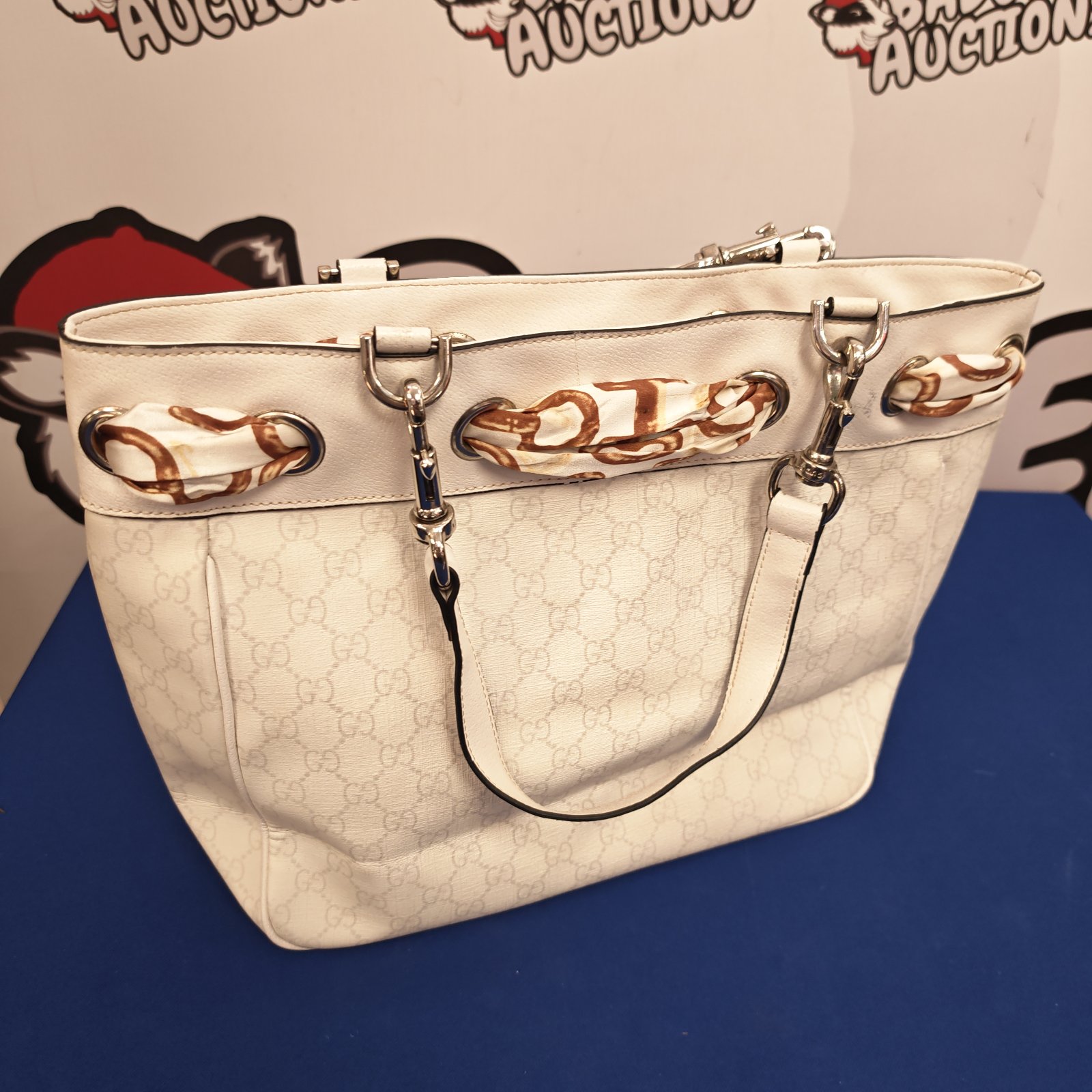 Cream Gucci handbag with logo pattern and gold hardware.