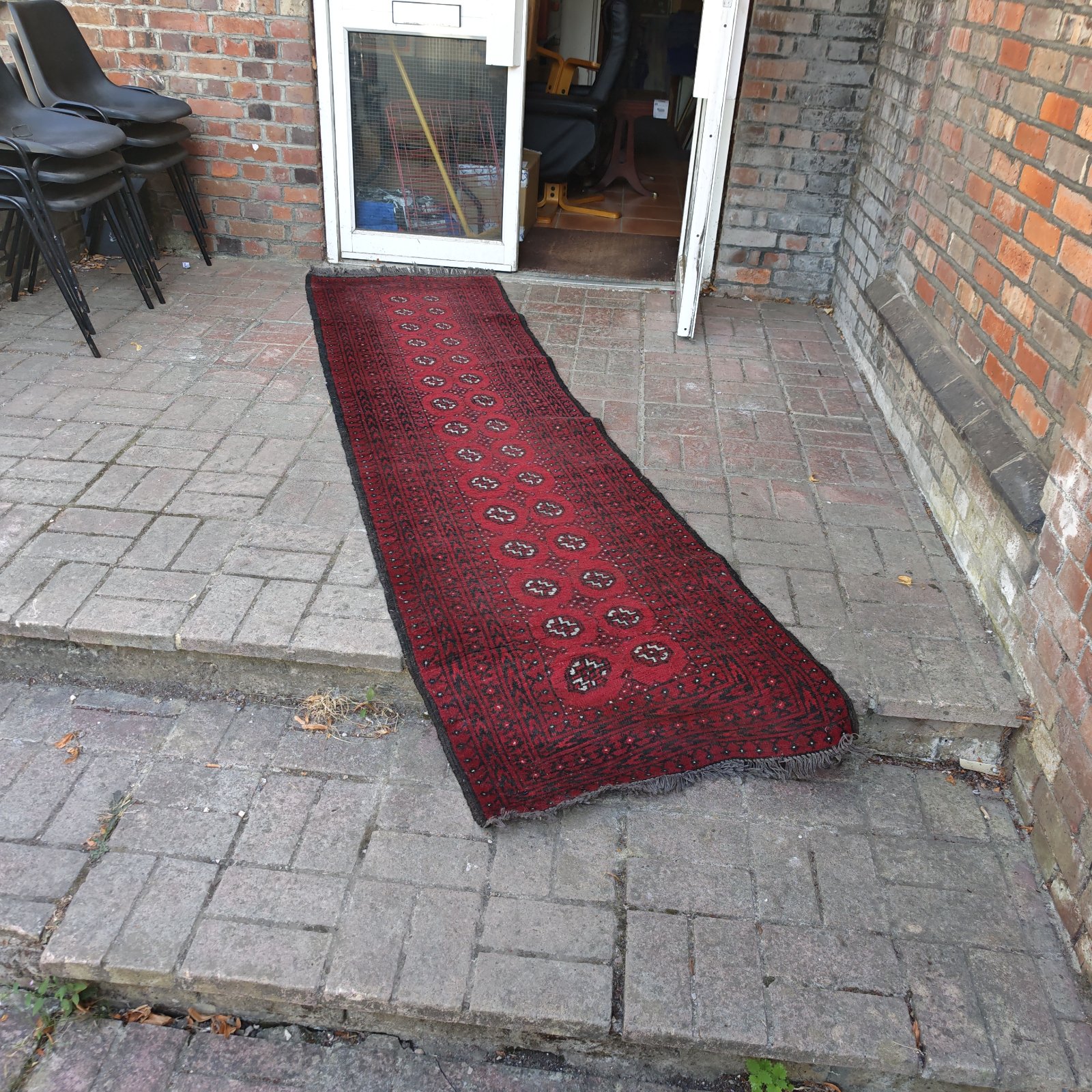Red hand knitted rug runner displayed in a hallway.