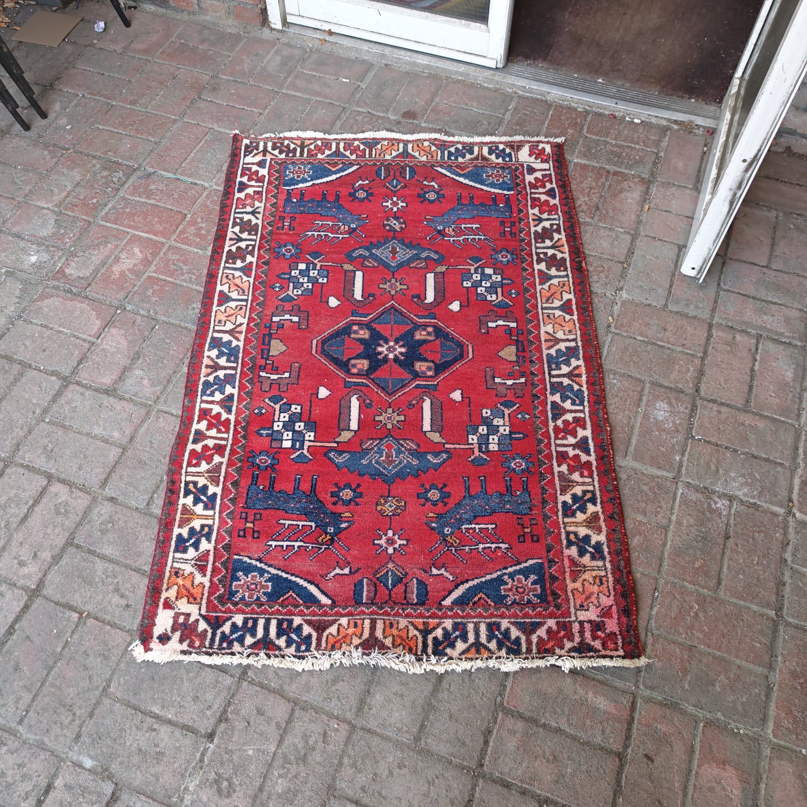 Vibrant hand knotted red rug with intricate tribal design.