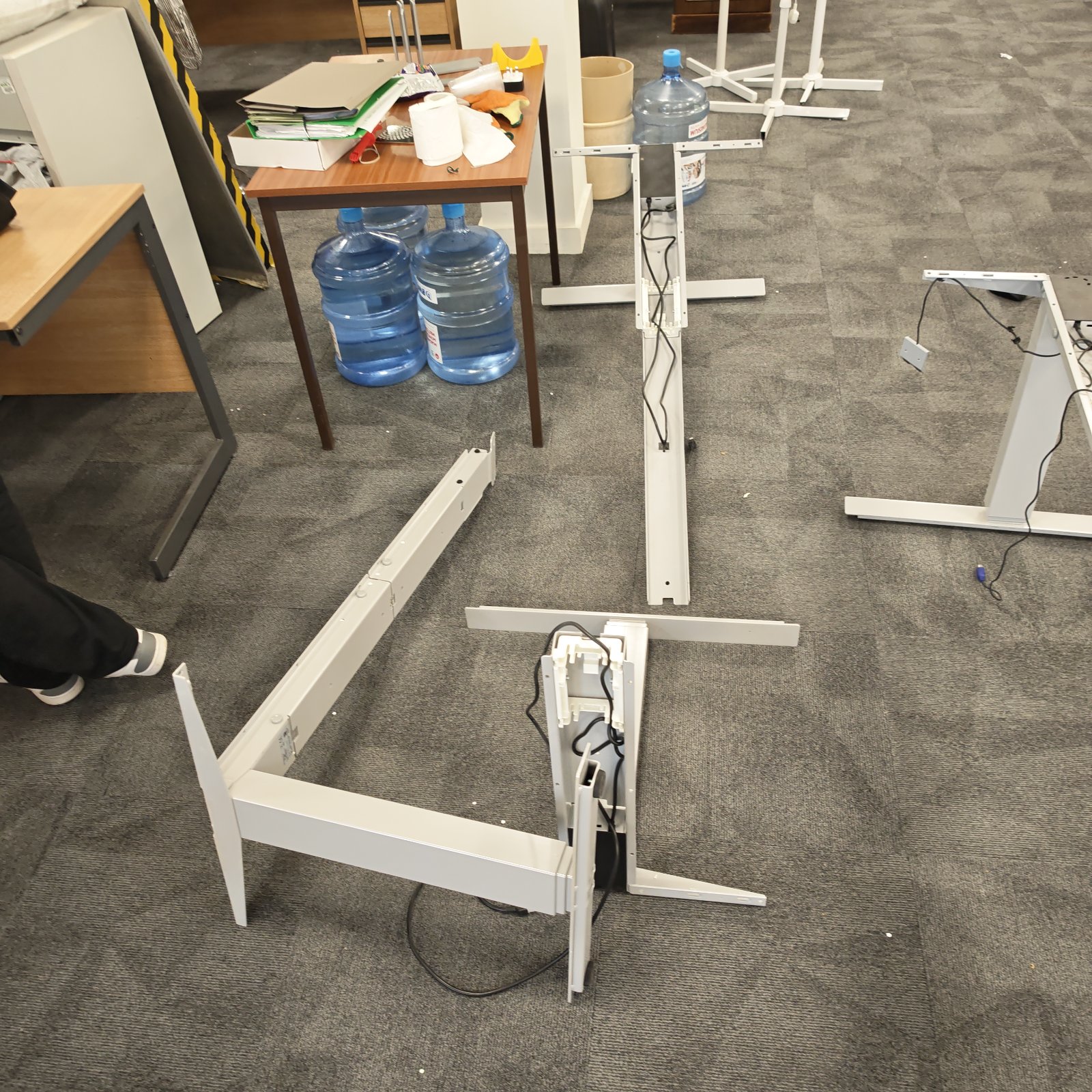 Disassembled height adjustable desk parts in an office setting.