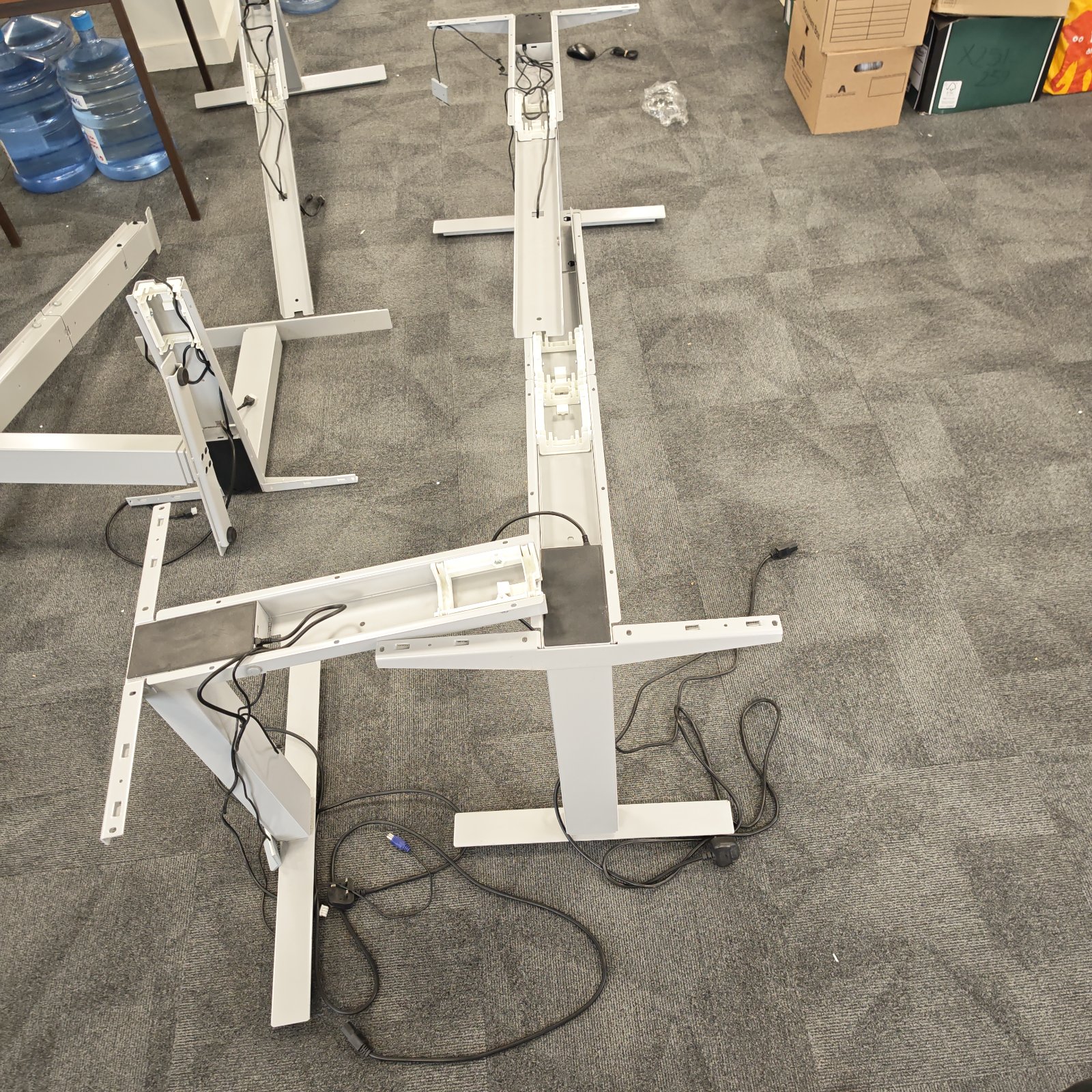 Disassembled height adjustable L shaped desk in an office setting.