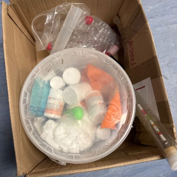 Assorted home distillery equipment in a plastic container.