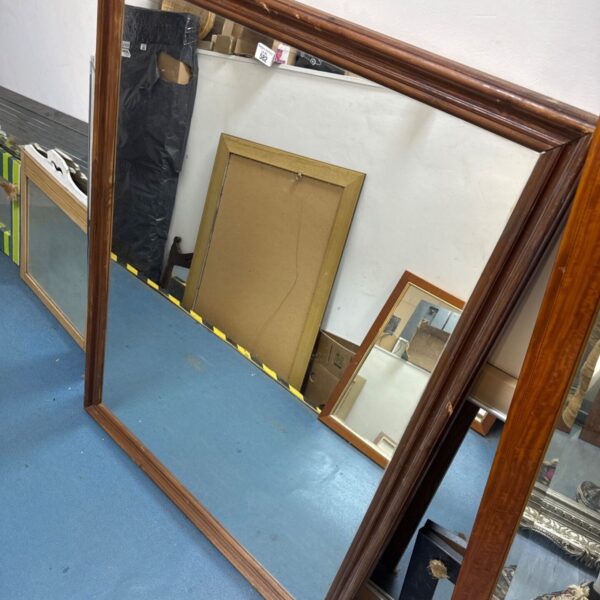 Large antique wood framed mirror reflecting a room.