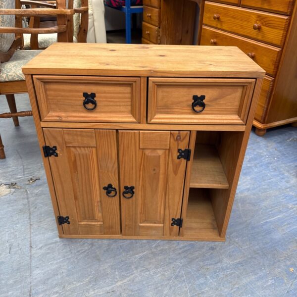 Light oak cabinet with drawers and a single door for storage.