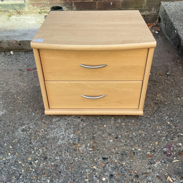 Light wood bedside cabinet with silver handles, ideal for bedroom storage.