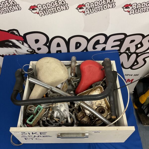 Box of spare bike parts including seats and handlebars