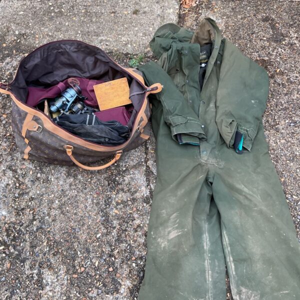 Vintage Louis Vuitton travel bag filled with fishing tackle and a jumpsuit.