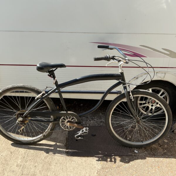 Matte black beach cruiser bicycle with black rims.
