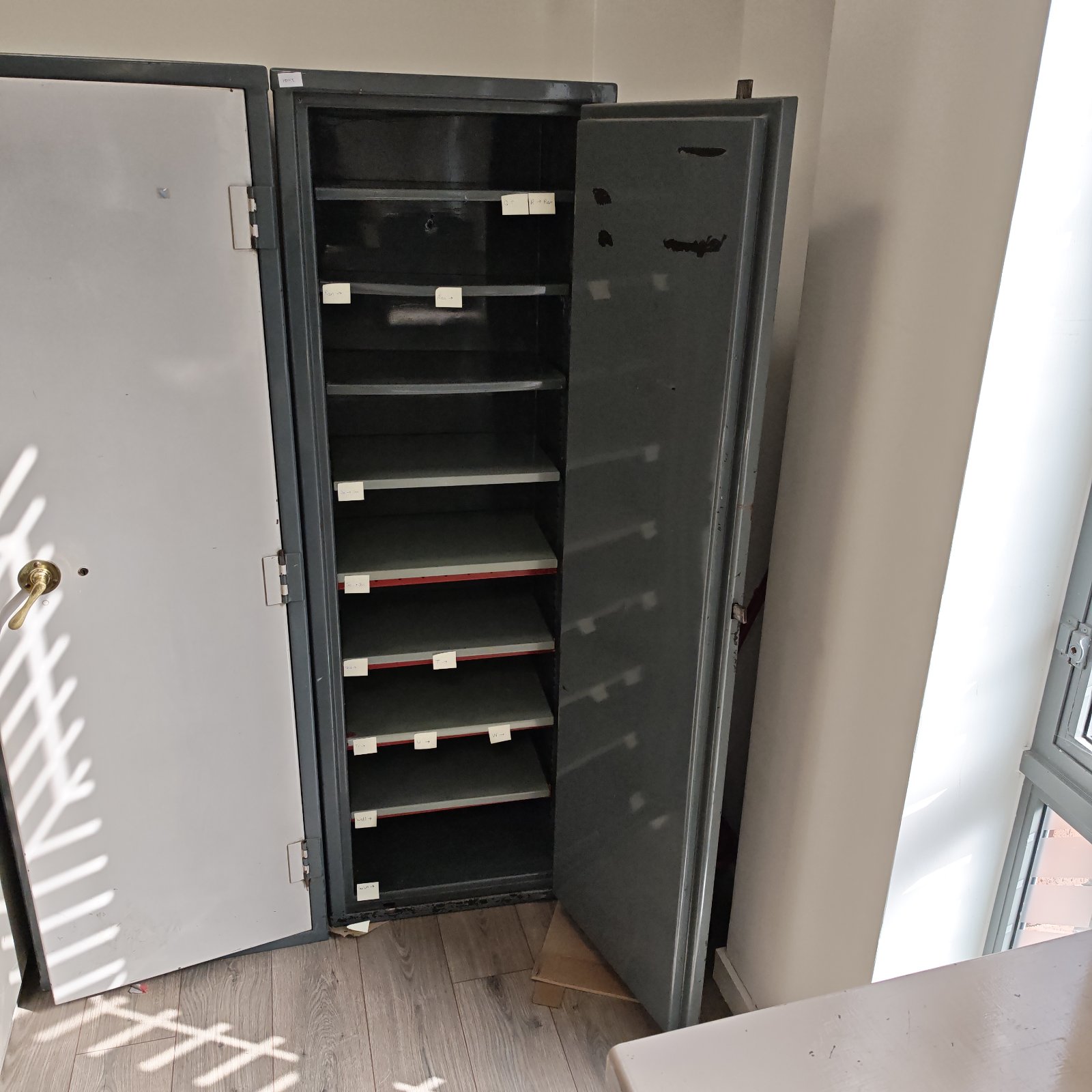 Open metal filing cabinet with shelves, secure office storage.