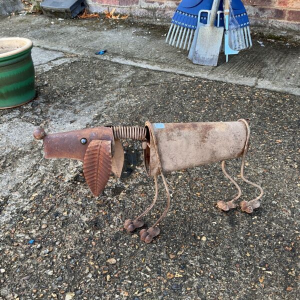 Rustic metal garden dog ornament in a garden setting.