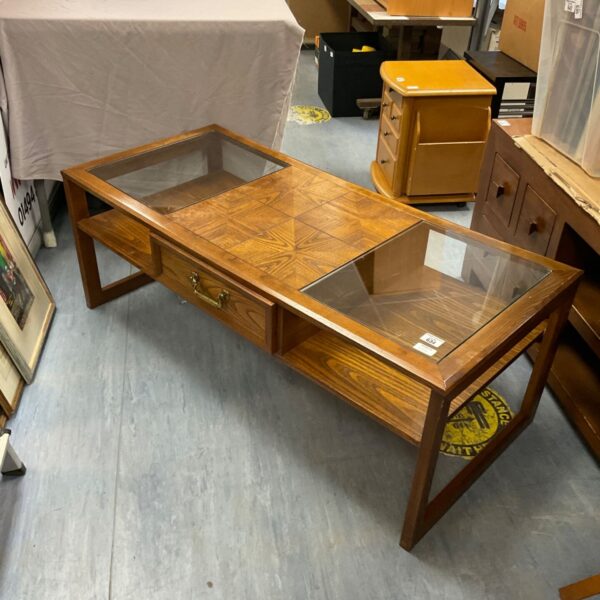 Vintage mid-century coffee table with glass top and wooden drawer.
