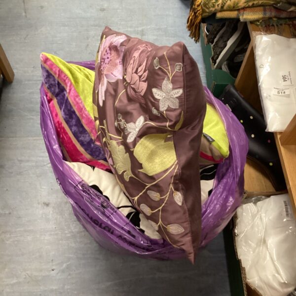 Purple bag filled with a mixed lot of patterned cushions.
