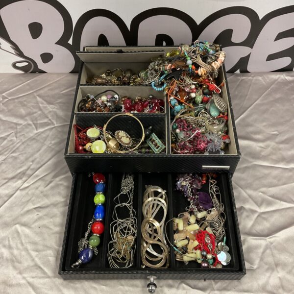 Mixed jewellery lot with necklaces, bracelets and rings displayed in a case.