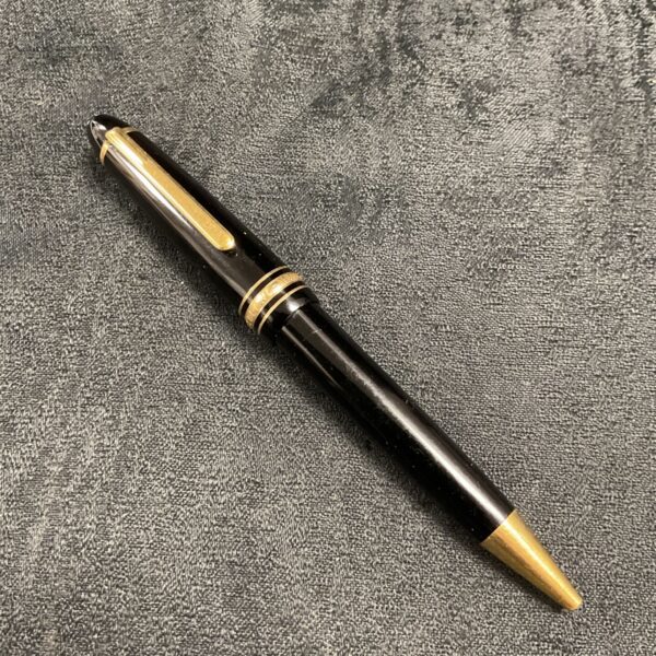 Black and gold Montblanc Meisterstuck ballpoint pen on textured fabric.