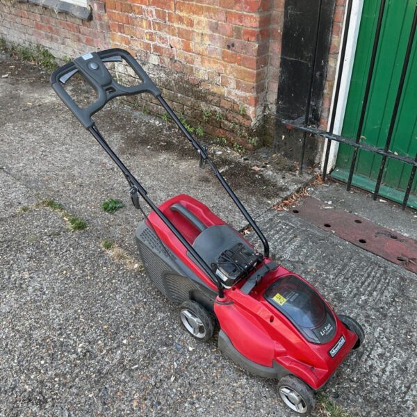 Red Mountfield Freedom500 cordless lawnmower in a garden setting.