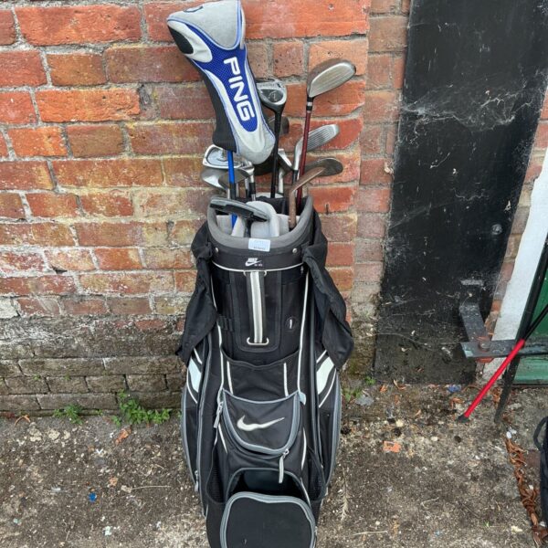 Nike golf bag with clubs leaning against a brick wall.