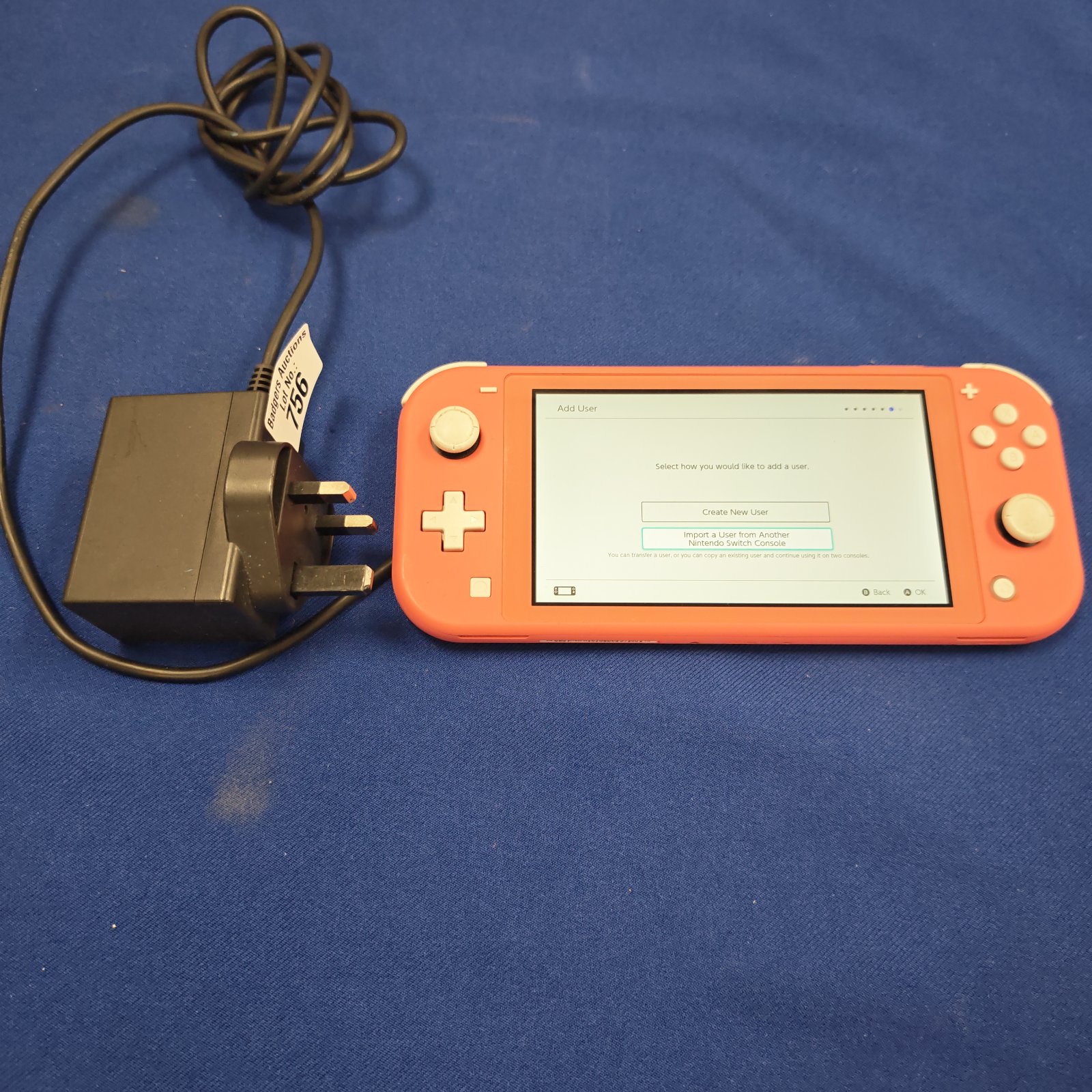 Coral Nintendo Switch Lite handheld gaming console with power cable.
