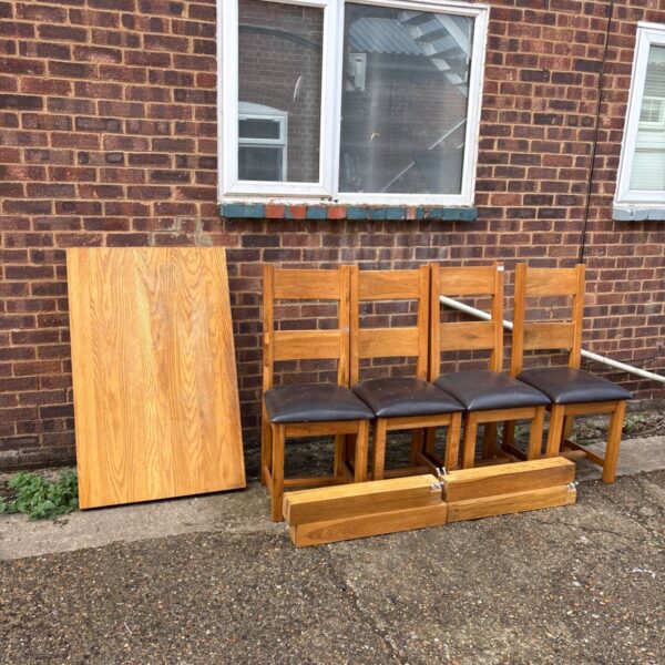 Solid oak dining table and four chairs in a rustic setting.