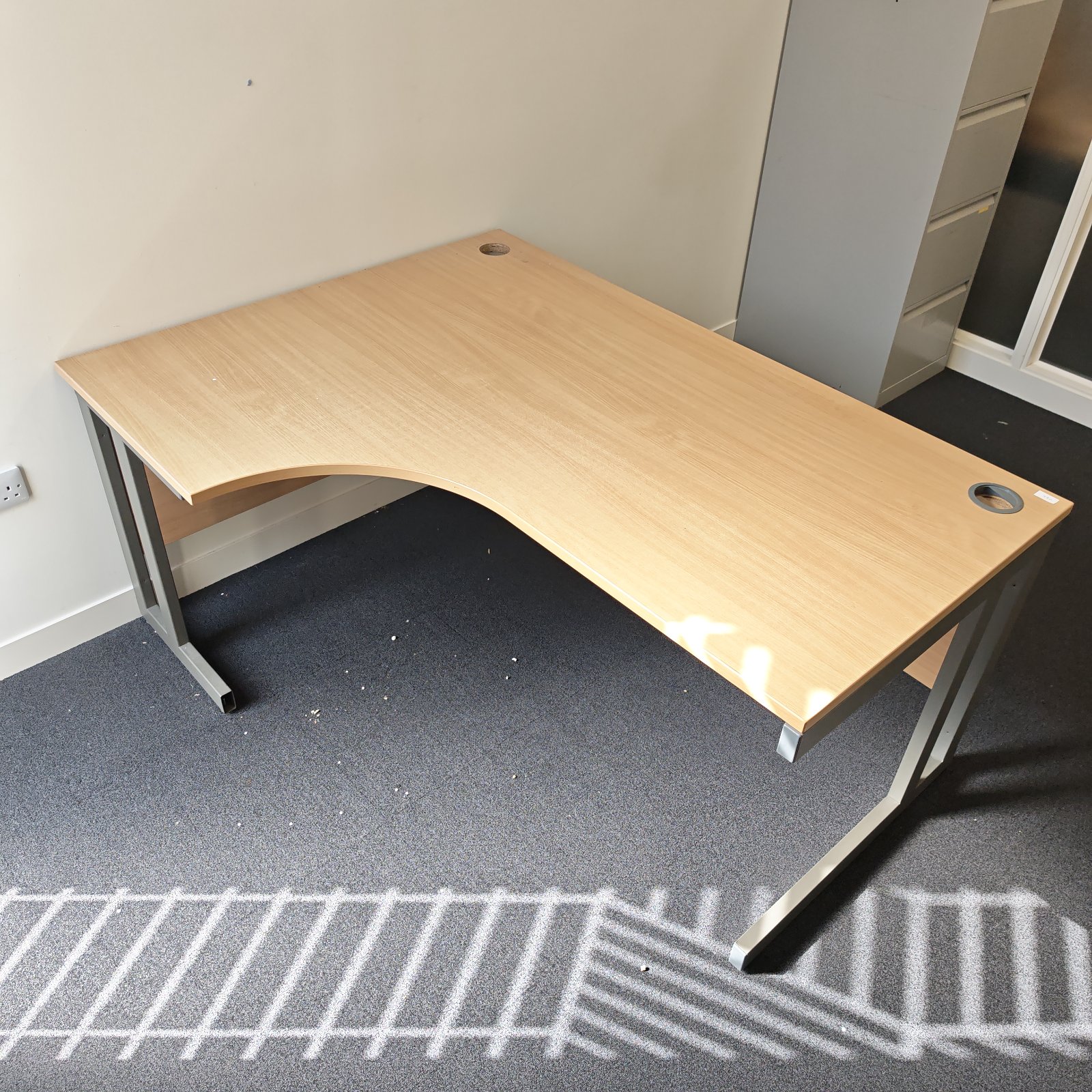 Wooden office corner desk with curved edge and metal legs.