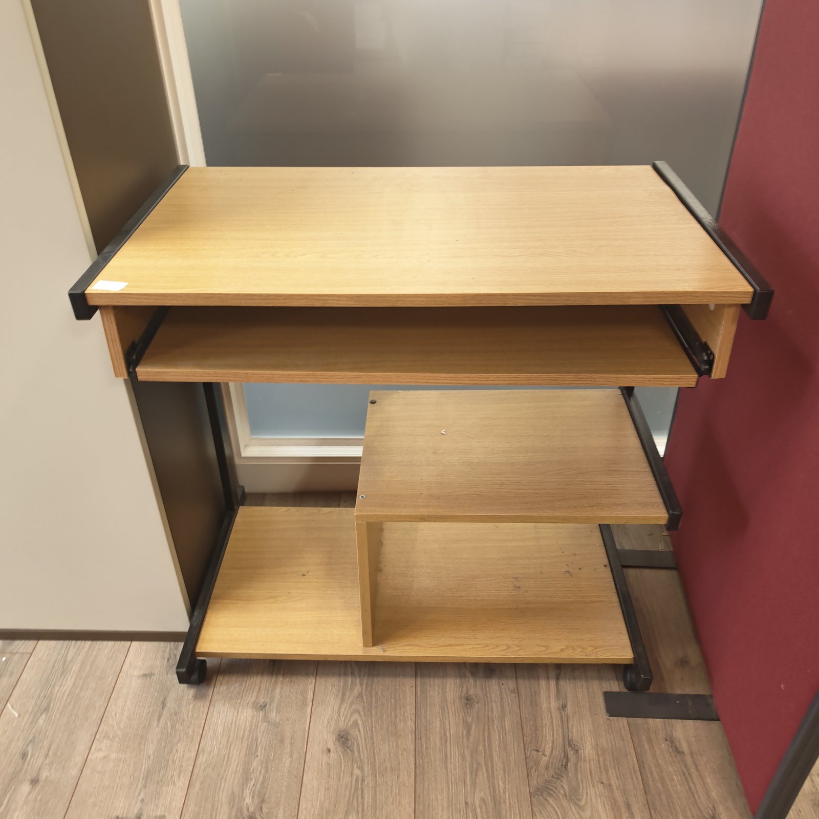 Rolling office desk with keyboard tray and storage shelf.