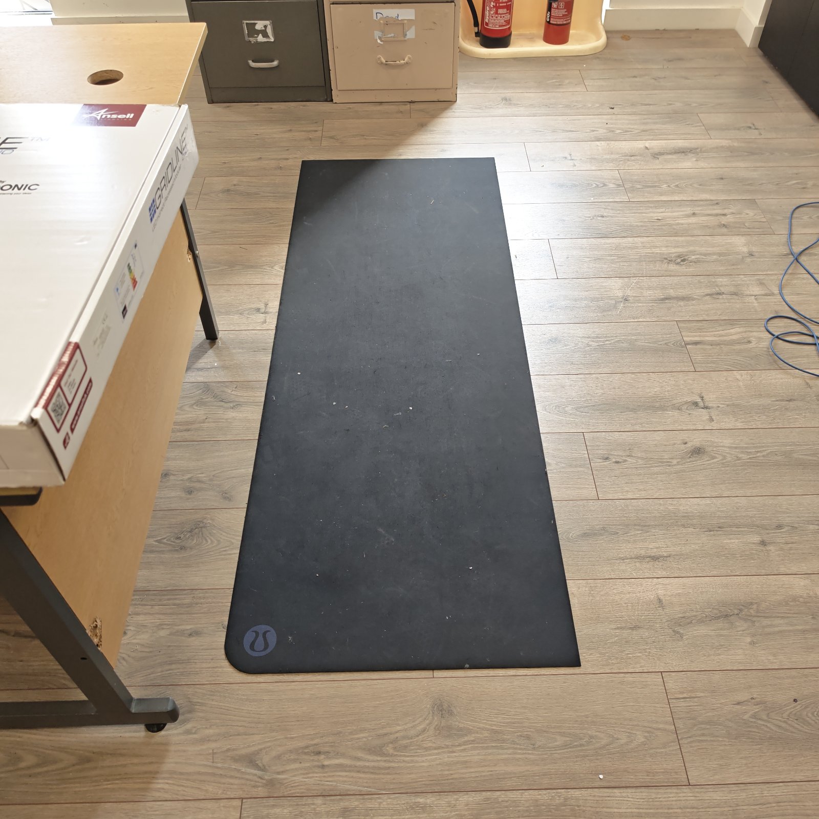 Black office floor runner mat on wooden flooring.
