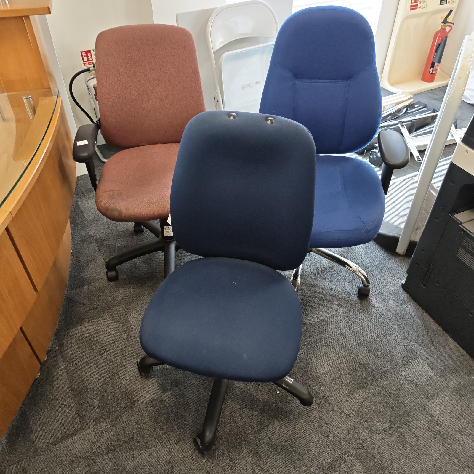 Lot of three office swivel chairs in blue, red, and brown.