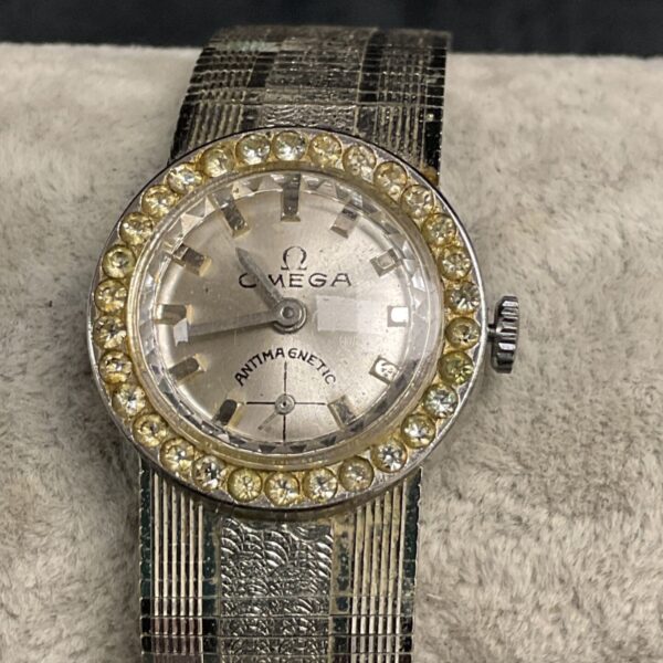 Vintage Omega ladies watch with gemstone bezel and textured bracelet.