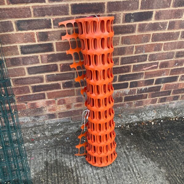 Roll of bright orange plastic fencing for temporary barriers.