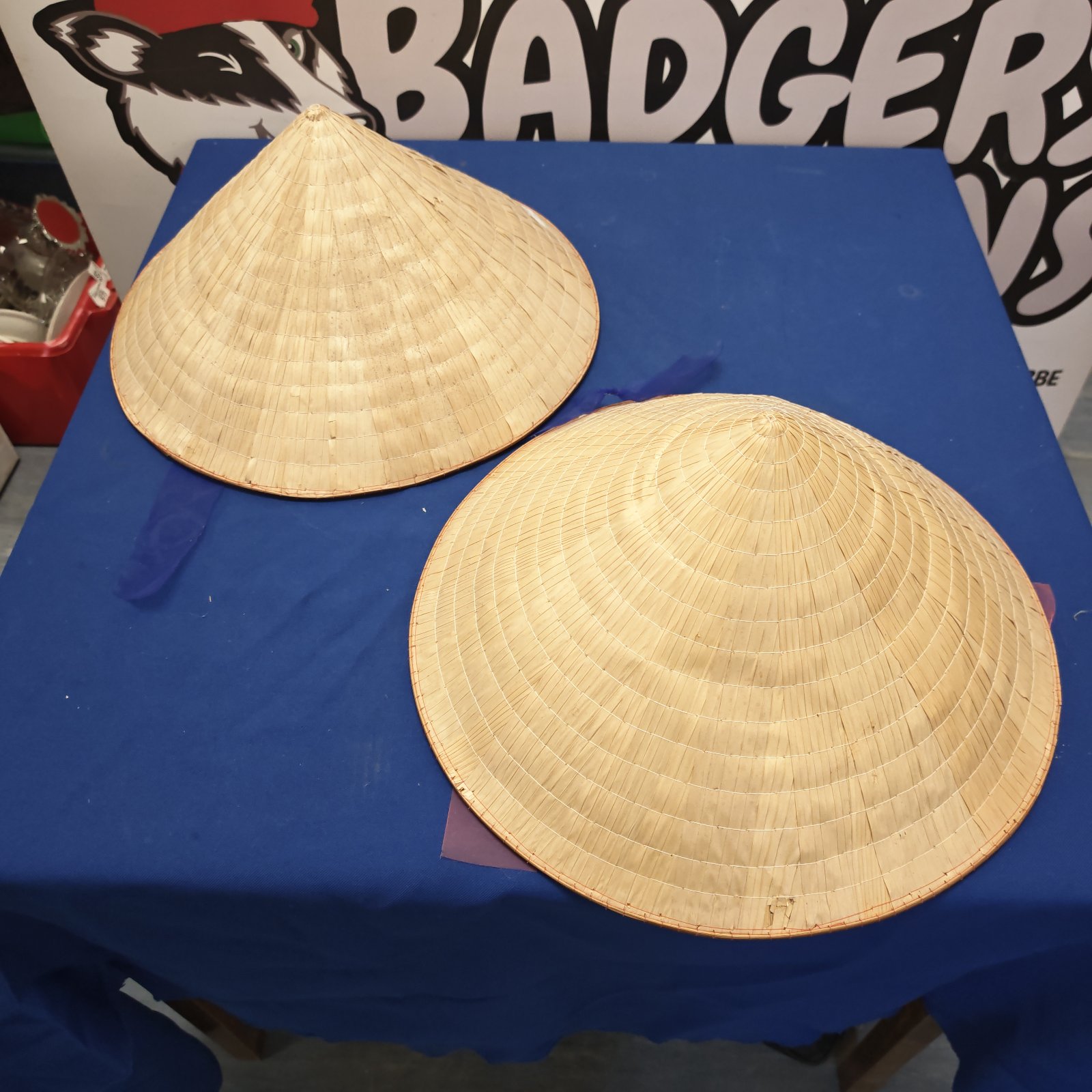 Two woven straw oriental hats displayed on a blue surface.