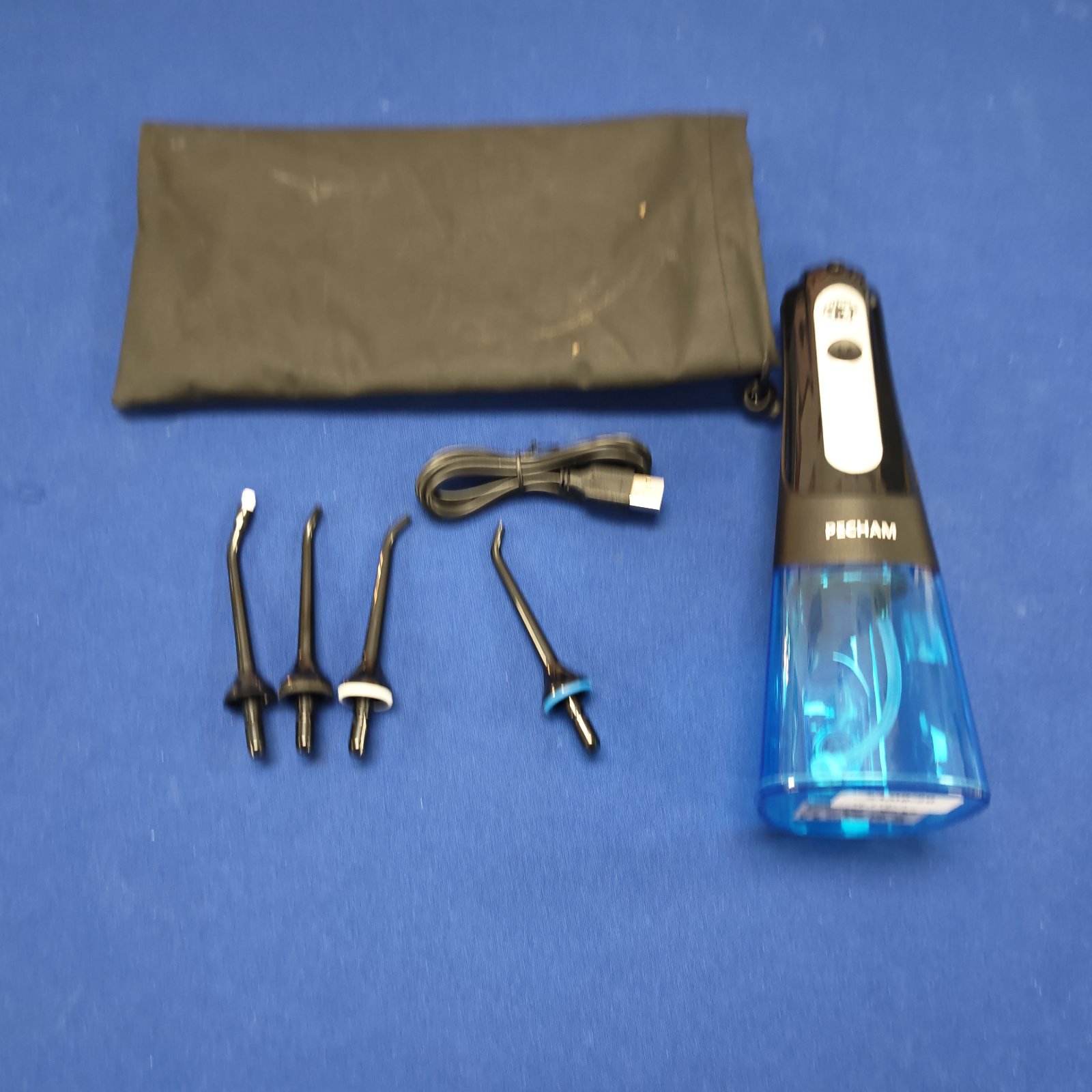 Blue Pecham electric oral irrigator with nozzle attachments.