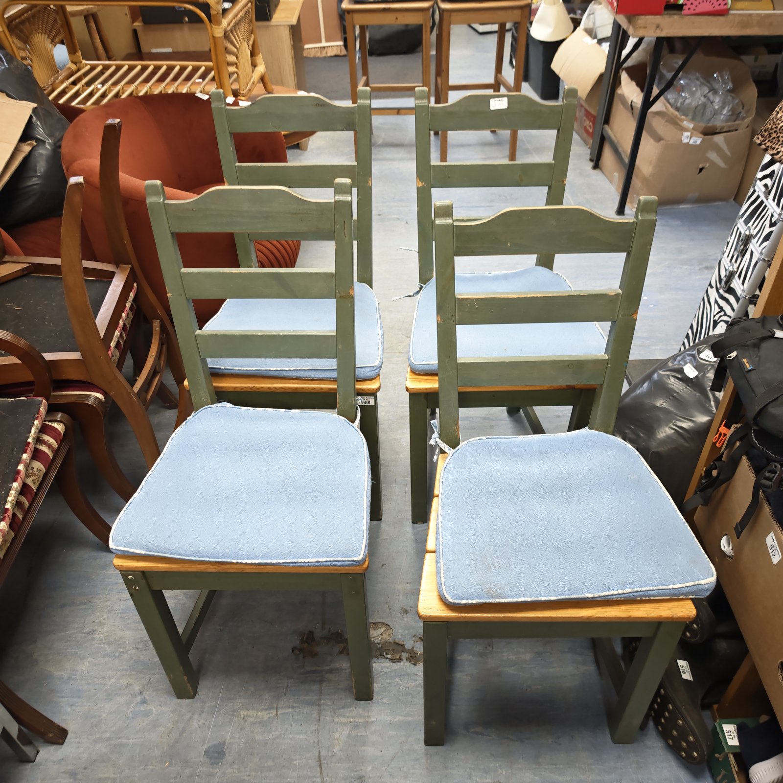 Four green pine dining chairs with blue seat cushions.
