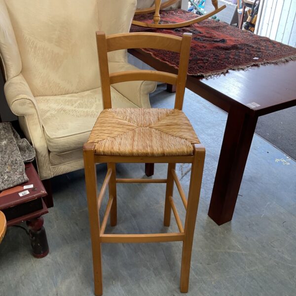 Rustic pine kitchen stool with woven raffia seat.