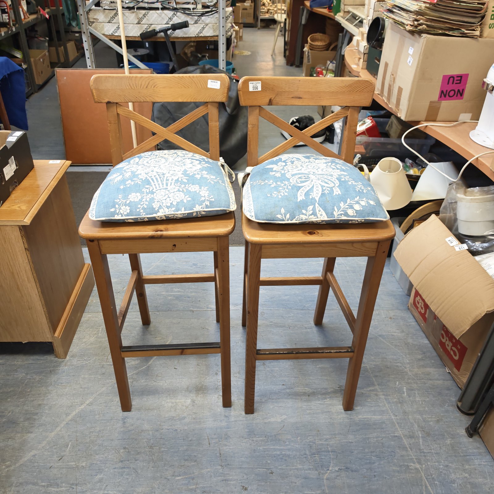 Two rustic pine stools with floral cushions for kitchen seating.