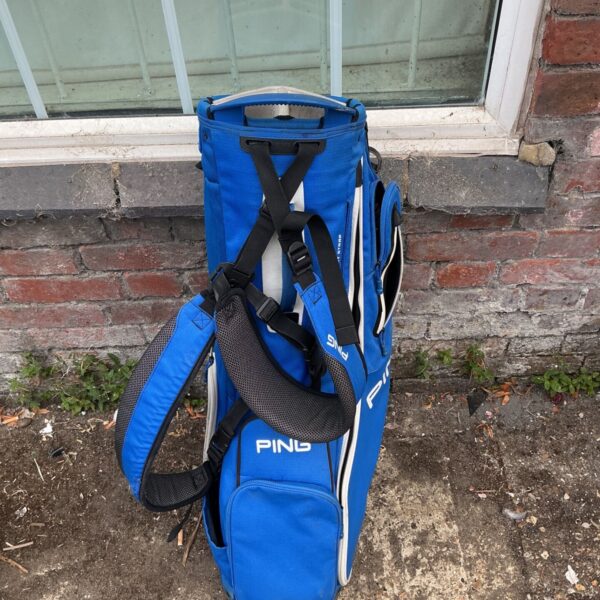 Blue Ping golf bag with shoulder straps and multiple pockets.