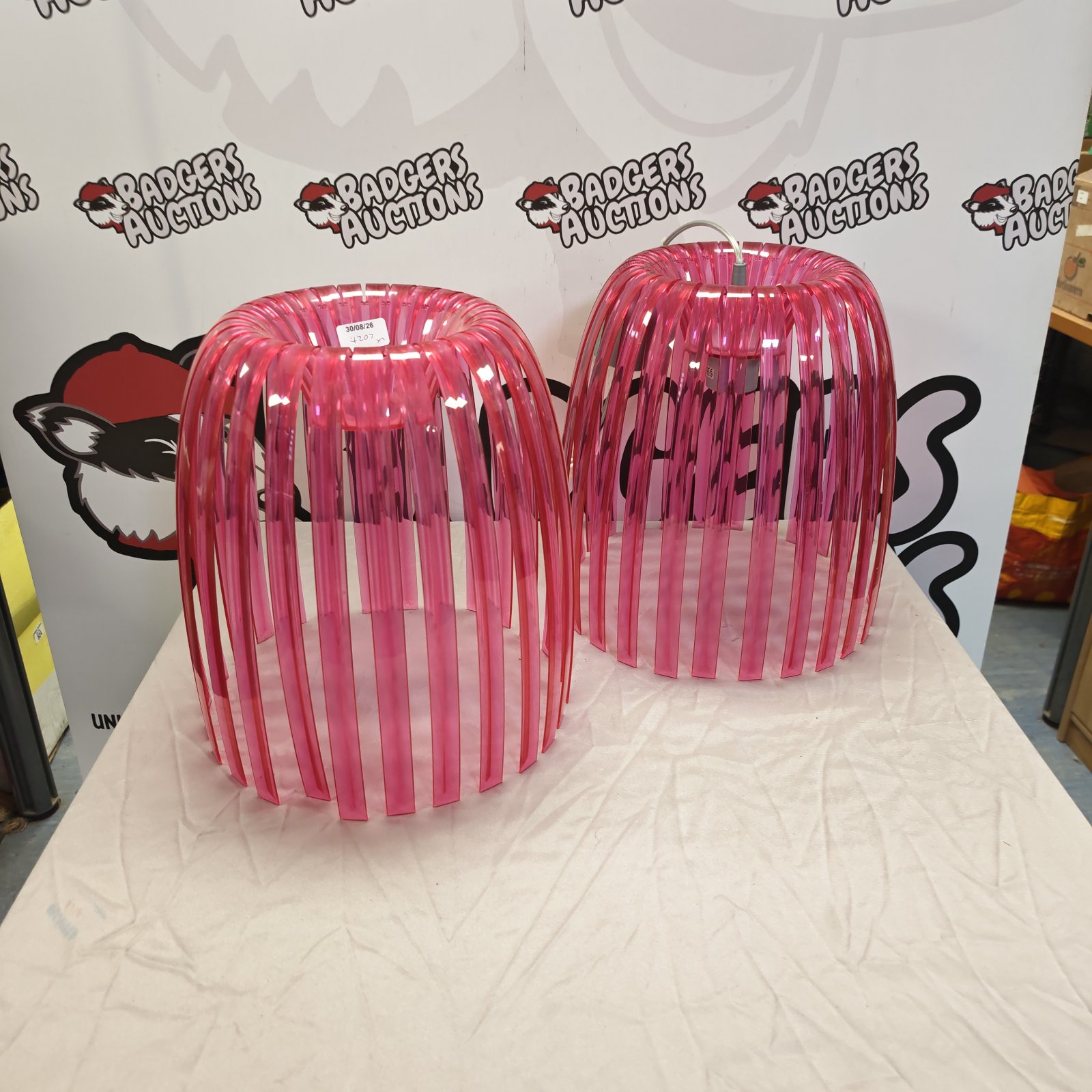 Two pink perspex ceiling light shades with a retro design.