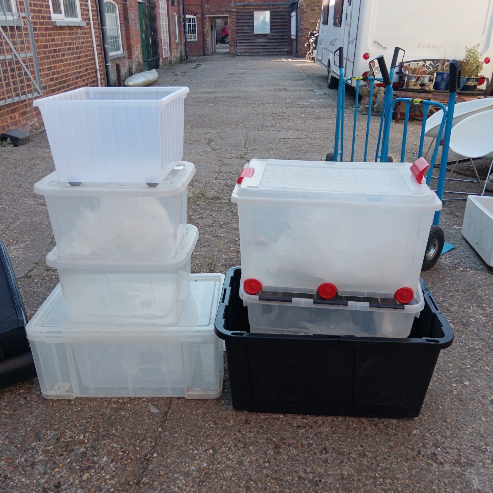 Large lot of clear and black plastic storage boxes for household storage.
