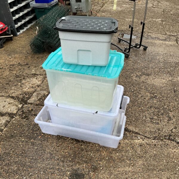 Lot of four used plastic storage boxes stacked together.
