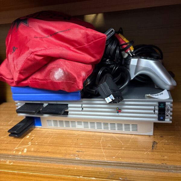 Silver PlayStation 2 console with controller and Buzz accessories.