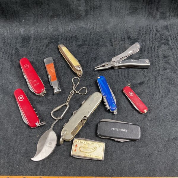 Assorted vintage pocket knives and multi-tools on a tray.