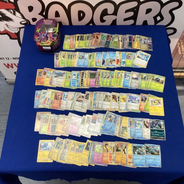 Assorted Pokemon cards inside a Mega Moonlit Collectors Tin.