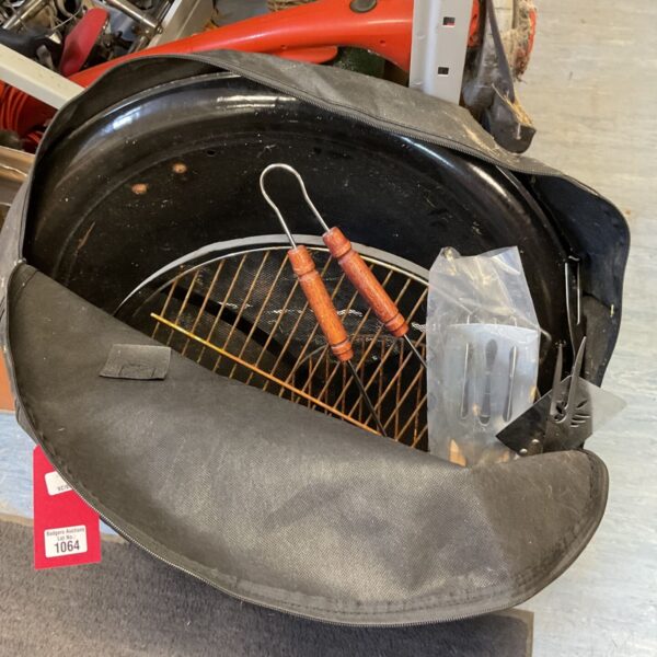 Portable BBQ grill with tools in a carry bag, ready for outdoor cooking.