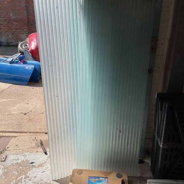 Two PVC corrugated sheets leaning against a wall.
