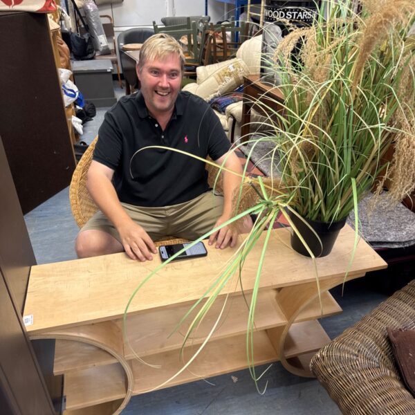 Man sitting in a vintage rattan tulip chair with a bentwood table.