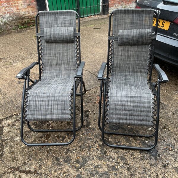 Pair of grey and white checked recliner sun chairs in a garden.