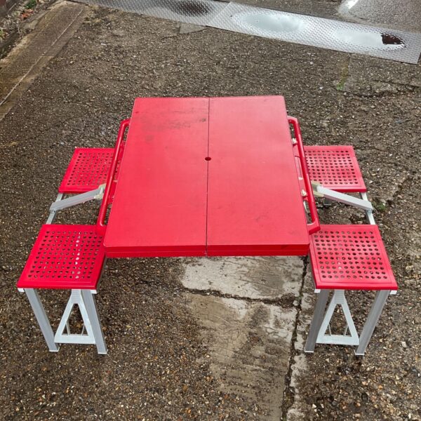 Red folding plastic bench in an outdoor setting.